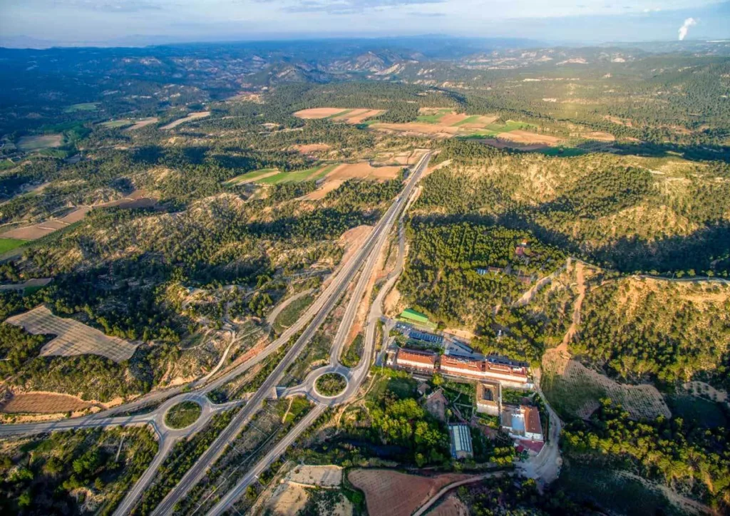 panorámica aérea del balneario de la concepción junto a la autovía, rodeado de montañas y campos en el valle del cabriel
