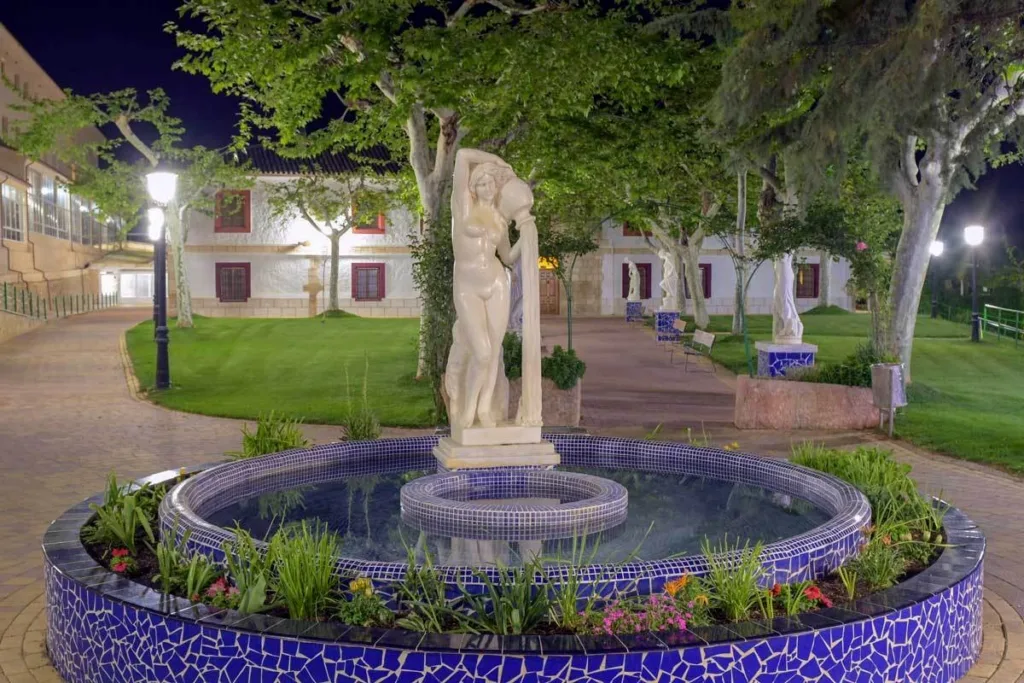 fuente con escultura clásica iluminada de noche en los jardines del balneario de la concepción en villatoya